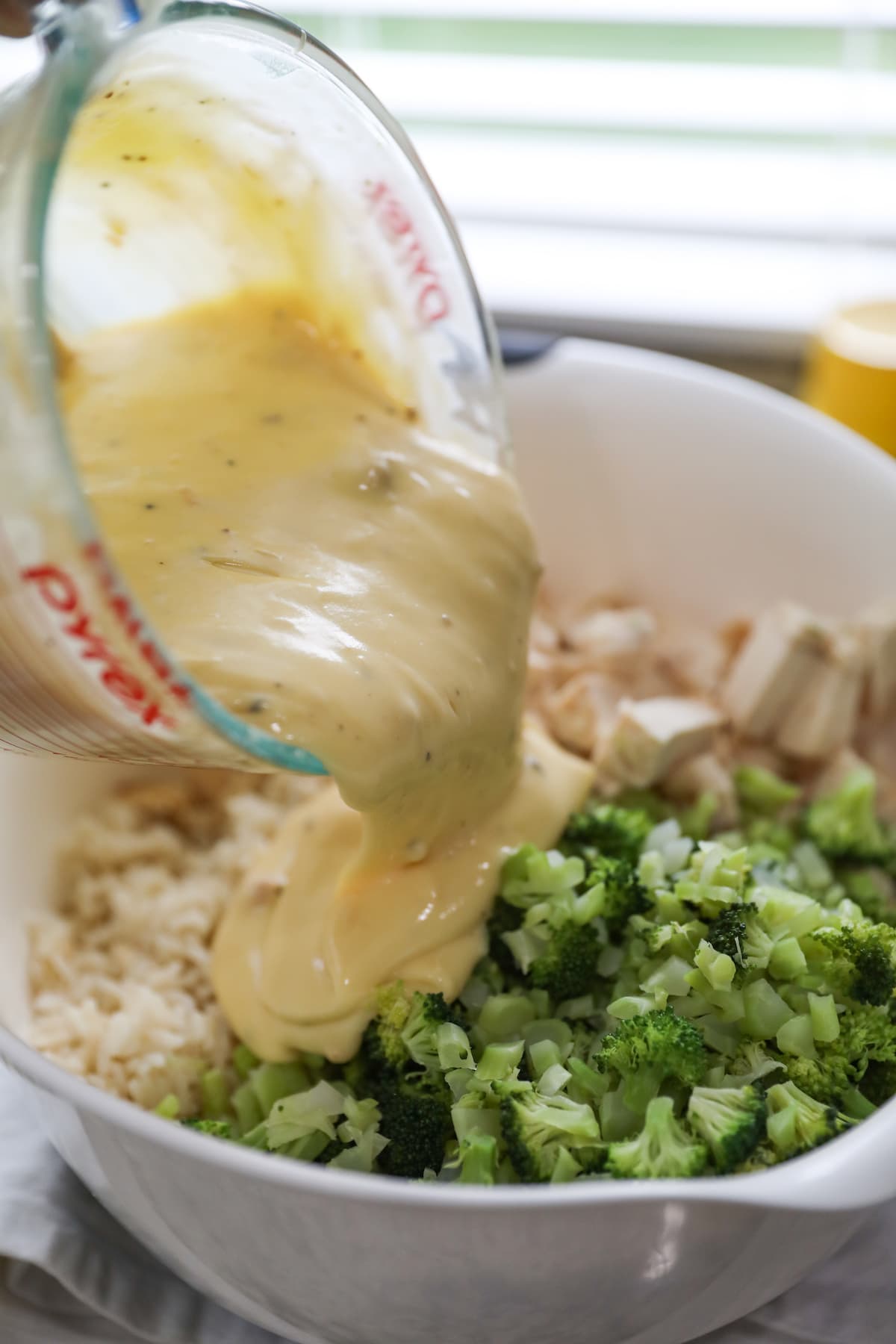 pouring sauce over rice, turkey and broccoli