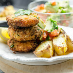 Salmon patties on a plate with skillet fries and avocado salsa