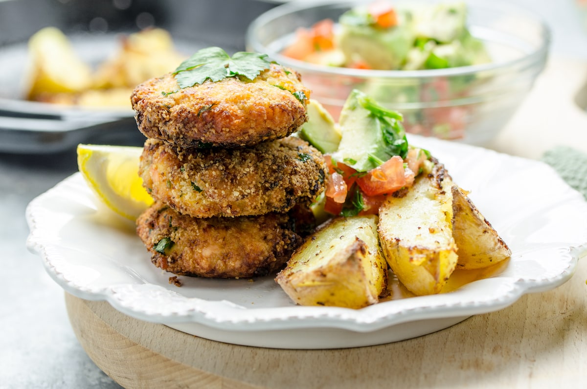 Salmon patties on a plate with skillet fries and avocado salsa