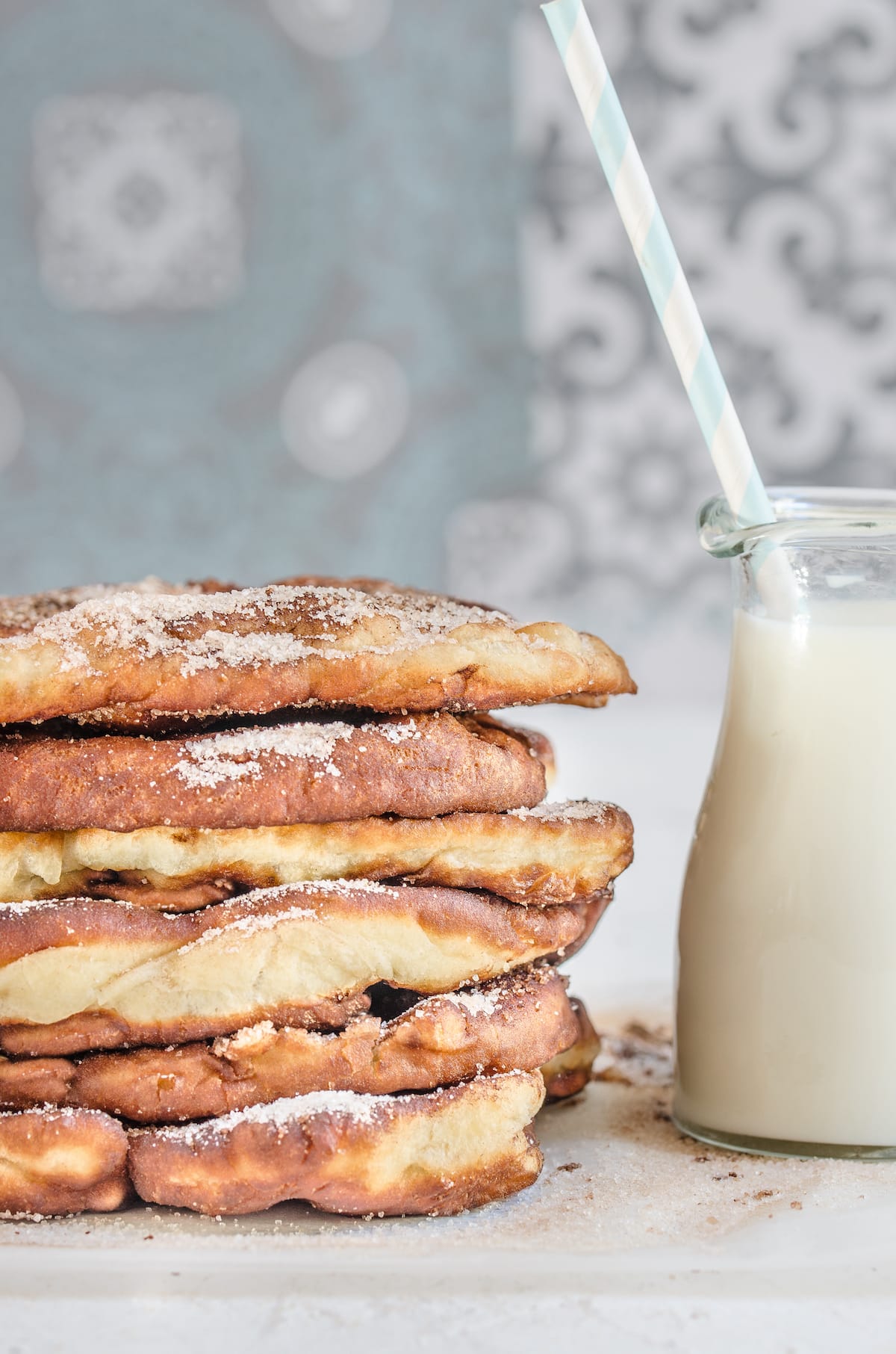 A stack of beaver tails fried dough next to a glass of milk
