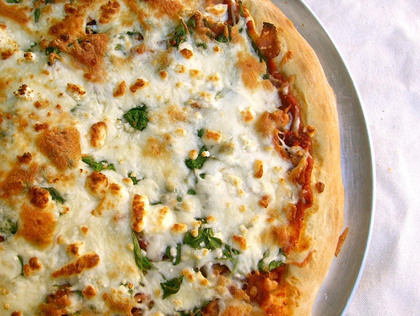 Spinach and Feta pizza on a pizza pan
