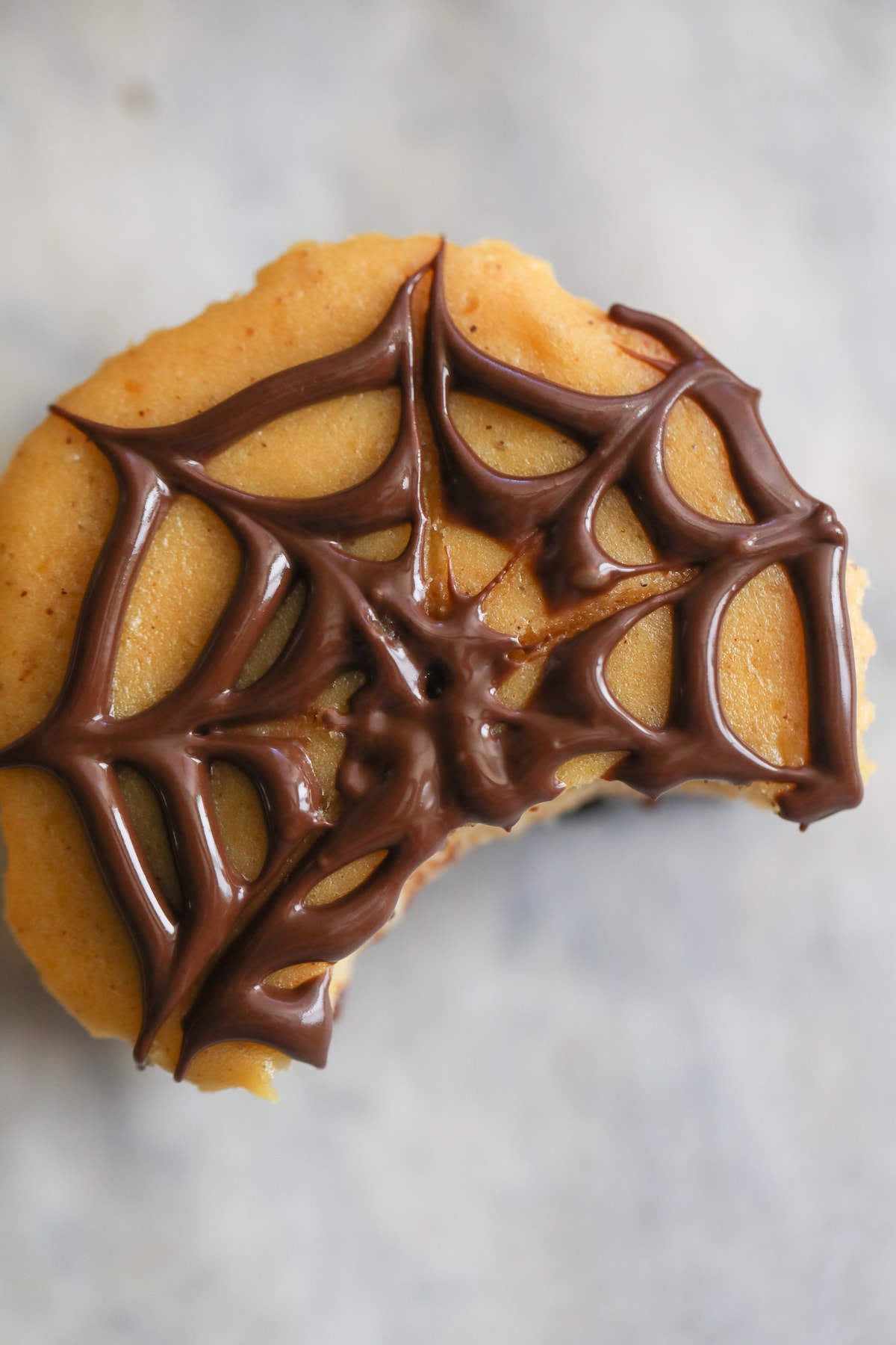 close up picture of pumpkin oreo cheesecakes with spider web