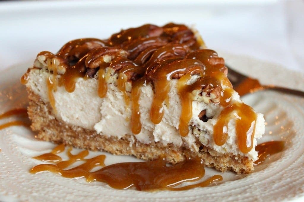 slice of Pecan Pie Cheesecake with caramel drizzled on top