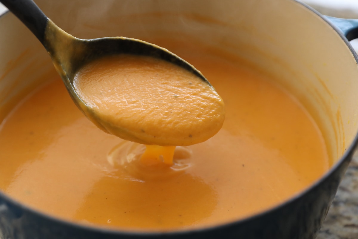 ladling carrot soup out of pot