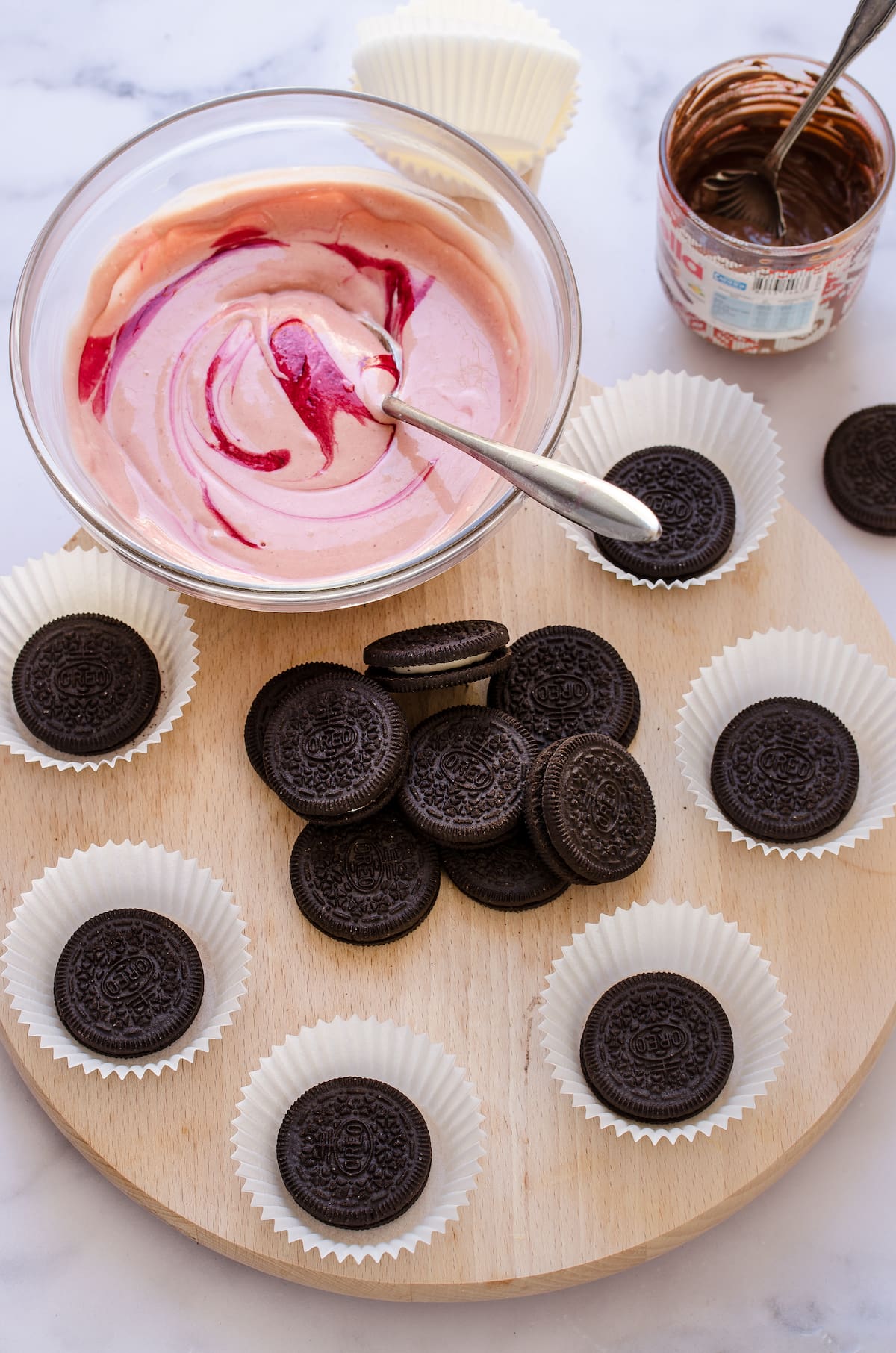 Oreos in cupcake liners and red velvet cheesecake batter in the background