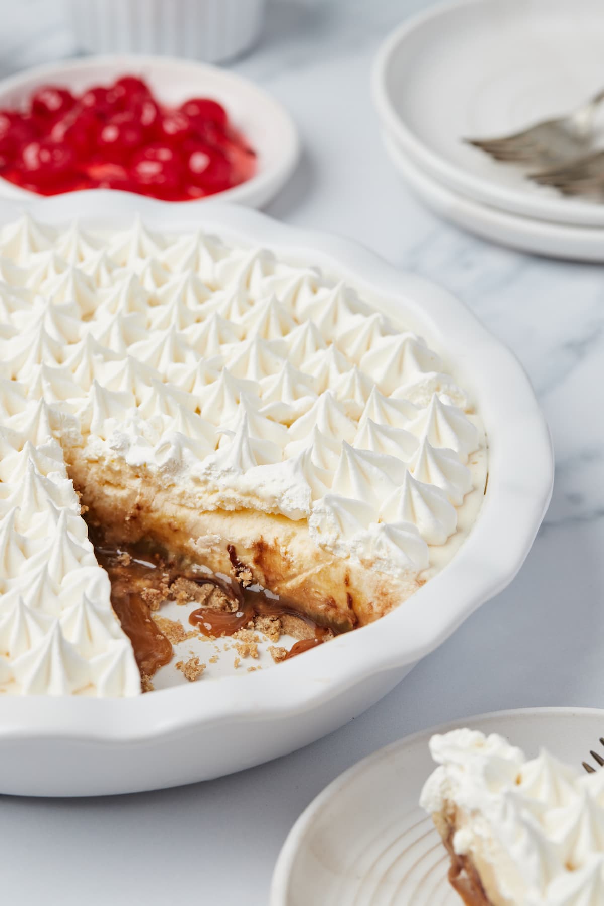 A no-bake pie topped with whipped cream rosettes. A slice has been cut out of the pie.