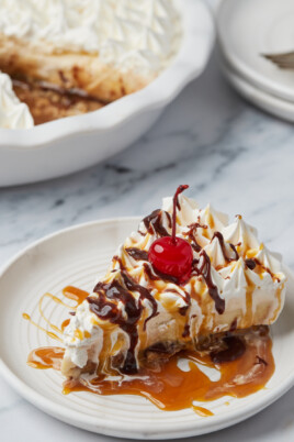 A slice of ice cream pie topped with caramel, chocolate sauce, and a cherry.