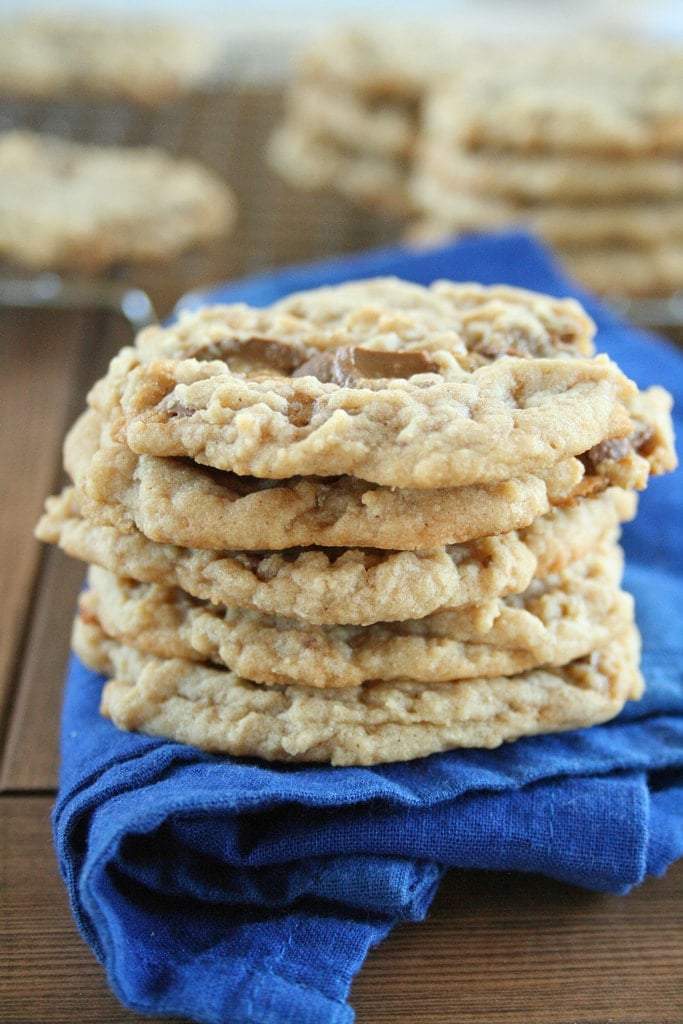 peanut butter caramel cookies stacked on top of each other all resting on a blue kitchen towel