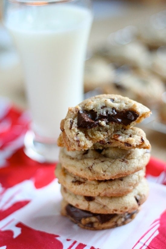 Dark Chocolate Chunk Cookies stacked on top of each other on a napkin. The top cookie has a bite taken out of it.