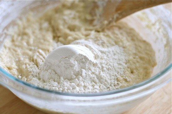 adding flour to dough mixture in a bowl