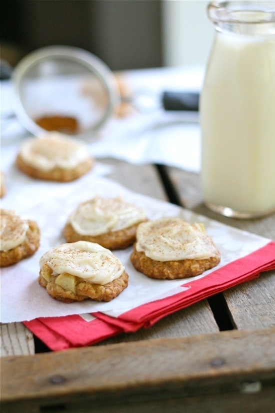 Apple Oatmeal Cookies with Brown Butter Frosting on parchment paper next to a glass of milk