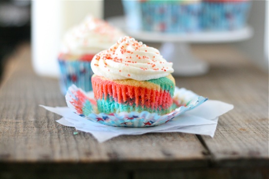 red white and blue cupcake with peeled cupcake liner all topped with frosting and sprinkles