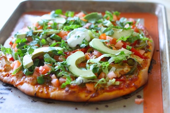 chicken fajita pizza on a baking sheet with lots of vegetable toppings