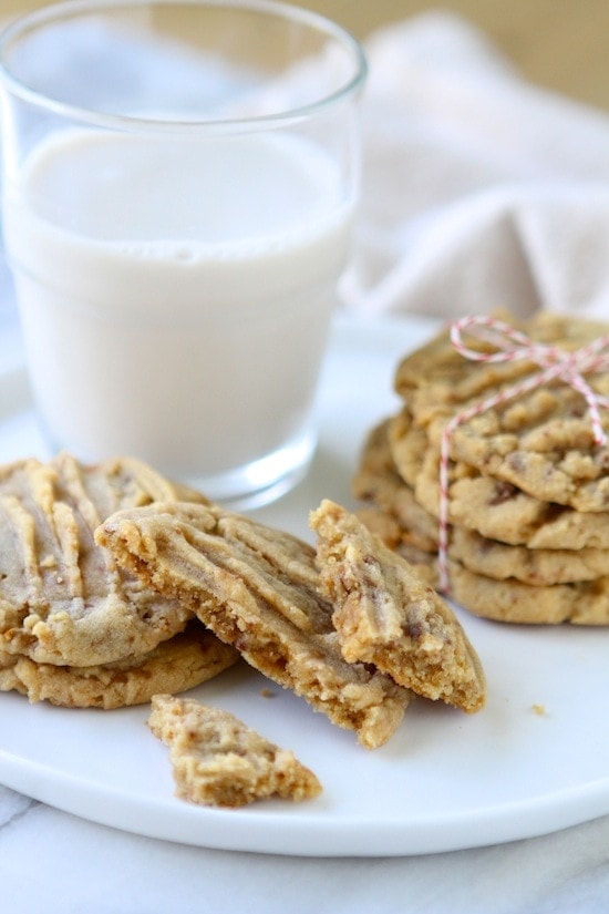 peanut butter toffee cookies assorted on a white plate with a glass of milk