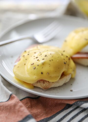 eggs Benedict on white plate with fork