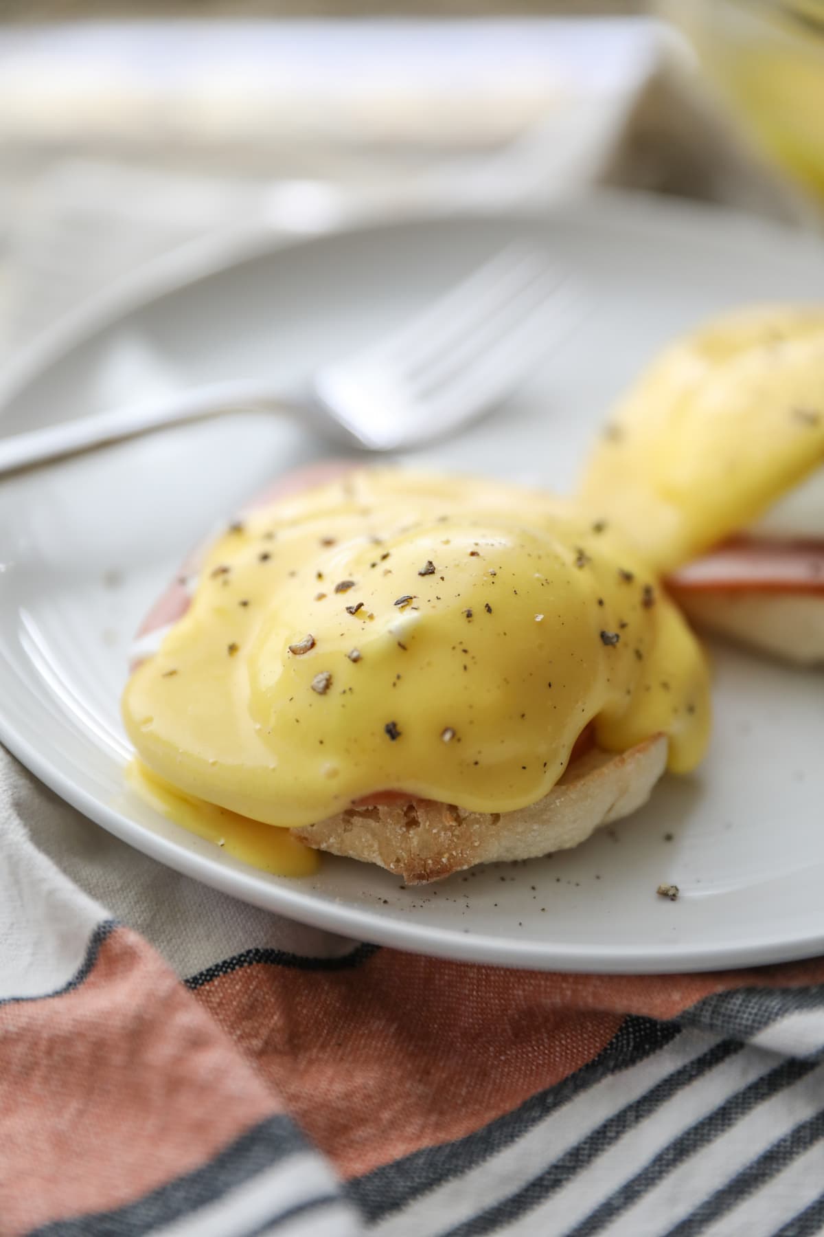 eggs Benedict on white plate with fork