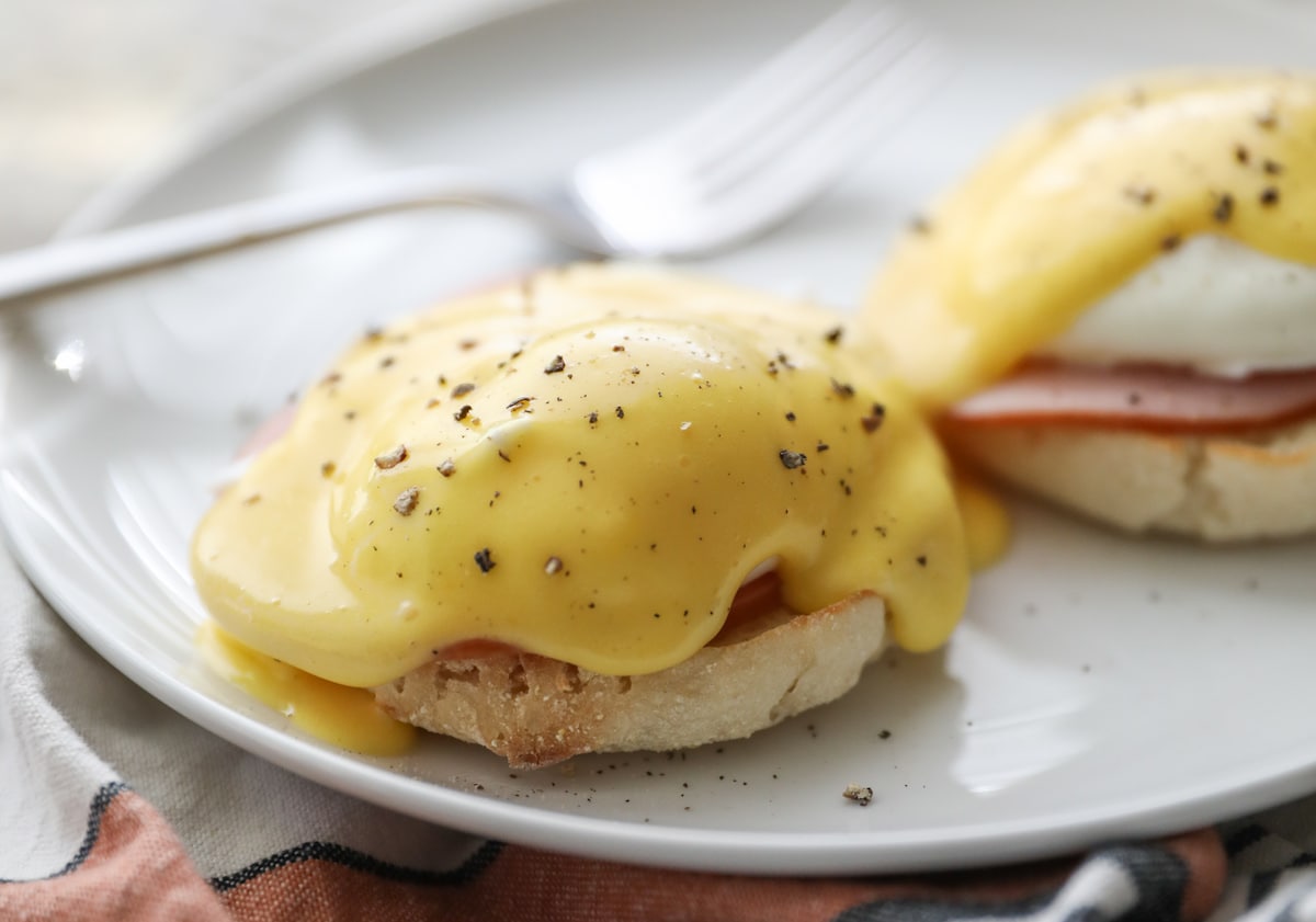Eggs Benedict on white plate with fork