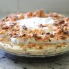 A Butterfinger pie topped with whipped cream and chocolate chips.