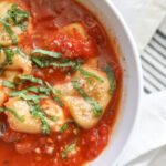 tomato basil tortellini soup in bowl with parmesan cheese