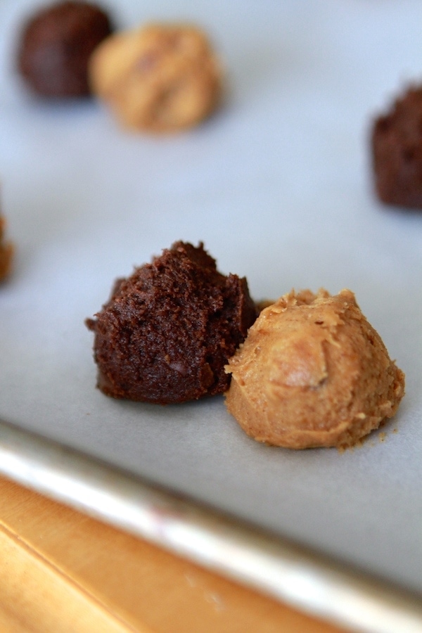 pumpkin and chocolate cookie dough balls next to each other on a parchment paper lined baking sheet