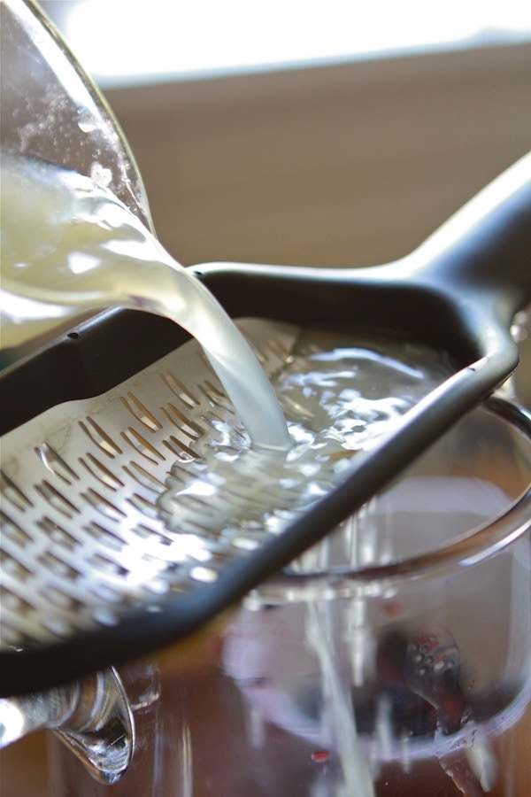 pouring fresh squeezed lemon juice over makeshift strainer