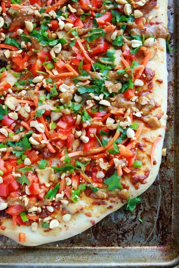 corner of baked thai chicken pizza with chopped veggies on it