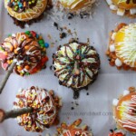 A tray of gourmet caramel apples with sprinkles and candy on top.