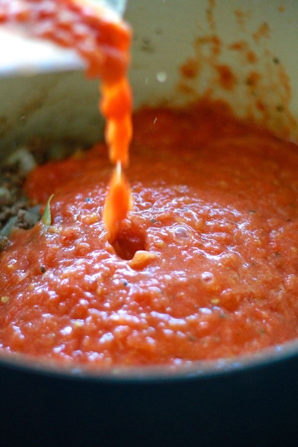 Adding tomato sauce to beef mixture