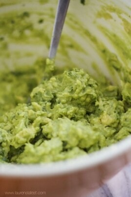 Super Bowl Guacamole in a white bowl with a spoon.