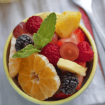A bowl of fruit salad with berries and mint.