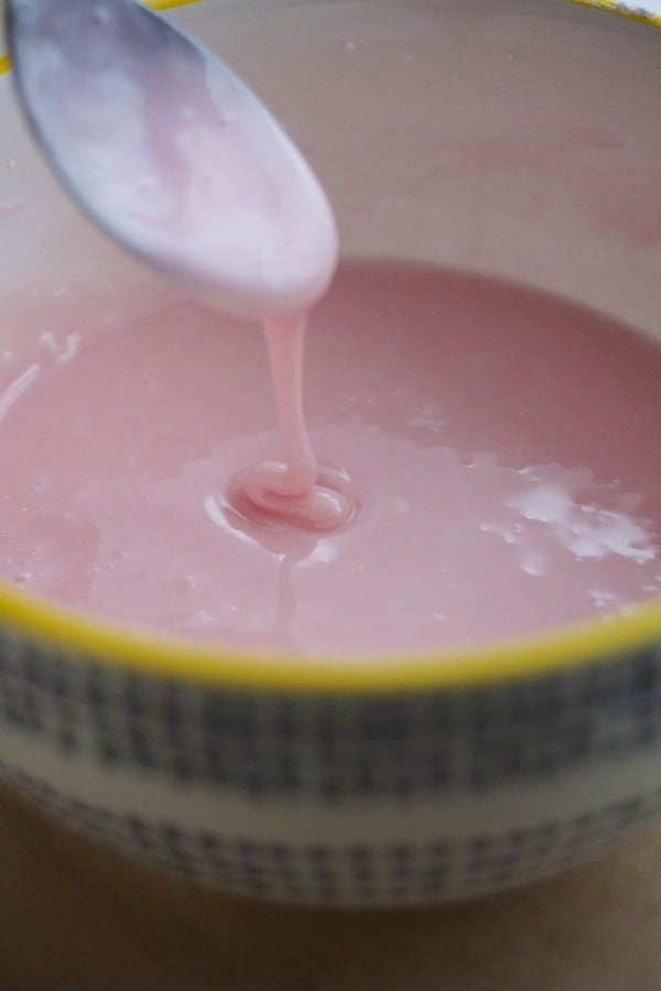 pink icing in a bowl with spoon