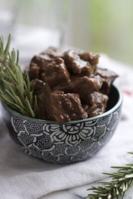 A crockpot of balsamic beef stew with rosemary and sprigs.