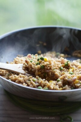 Fried rice being stirred in a pan with a wooden spoon.