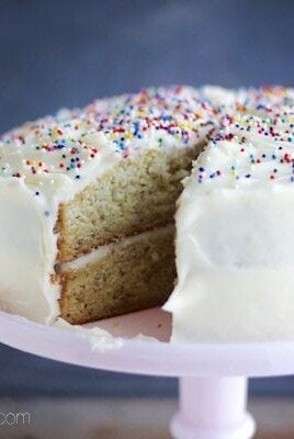 A banana cake with sprinkles on a pink cake stand.