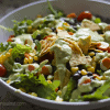 A bowl of salad with black beans, corn and avocado topped with sweet and spicy chicken.