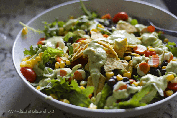 A bowl of salad with black beans, corn and avocado topped with sweet and spicy chicken.