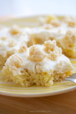 Lemon bars on a yellow plate with a fork.