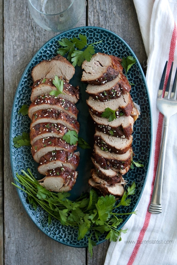 Sliced pork on a blue plate with herbs and a fork, served with ranch dressing.