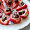 Deviled Strawberries topped with chocolate and nuts on a plate.