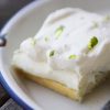 A slice of cake with whipped cream and lime on a plate.