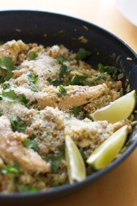 Chicken and rice in a skillet with lime wedges.
