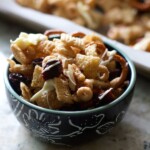 A bowl of cheesy granola with nuts and pretzels, perfect for snacking.