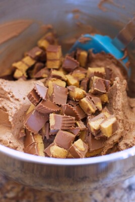A bowl full of chocolate pieces, topped with Reese's Peanut Butter Cup Frosting.