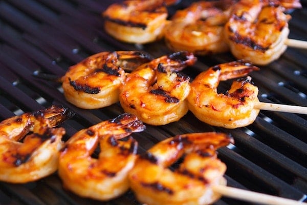 Sriracha shrimp skewers grilling on a grill.