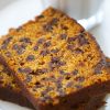 Indulge in a slice of chocolate chip pumpkin bread on a plate with a glass of milk.