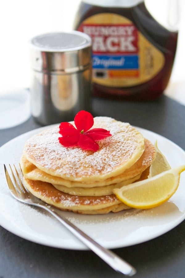 lemon ricotta pancakes dusted in powdered sugar on a white plate