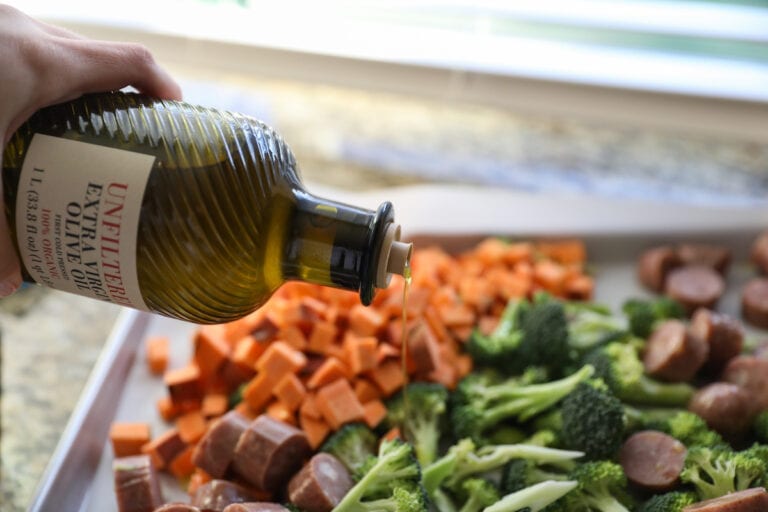 pouring olive oil onto vegetables and sausages