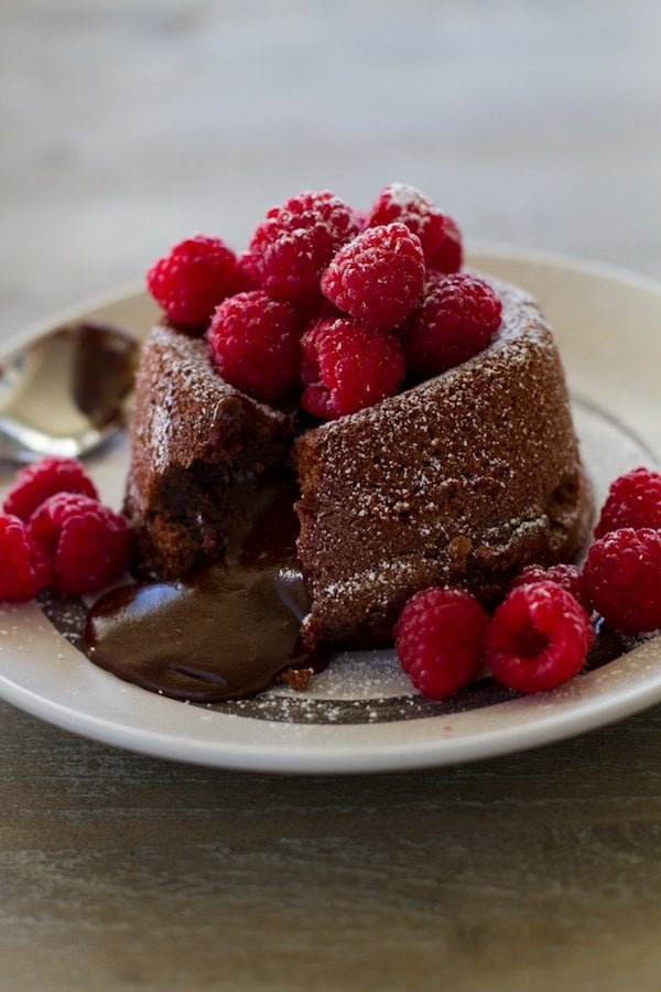 Lava Cake oozing out chocolate with raspberries and powdered sugar on top