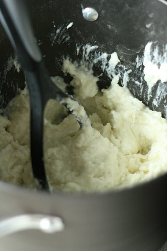 mashed potatoes in pot with potato masher