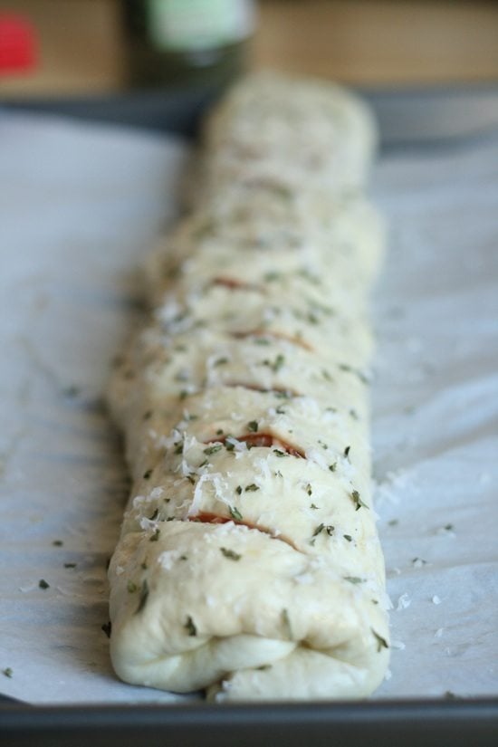 stromboli dough rolled up with slats and herbs on top